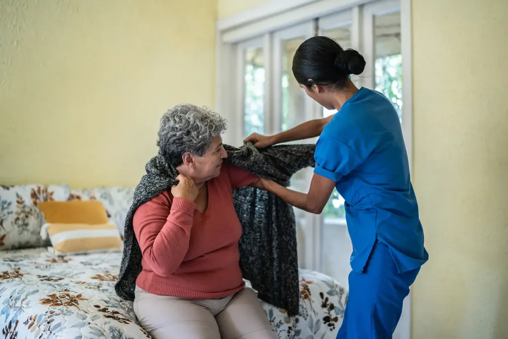 Home caregiver assisting a senior with dressing and daily living activities